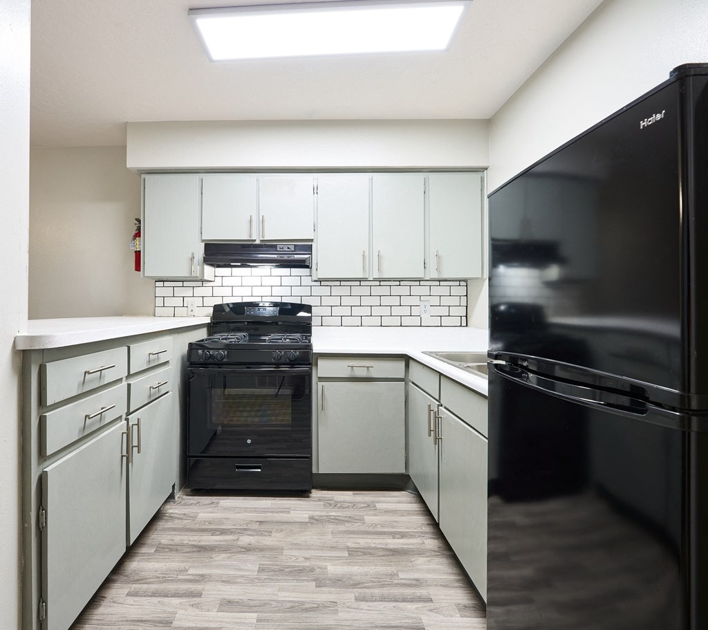 an empty kitchen with white cabinets and a black stove and refrigerator