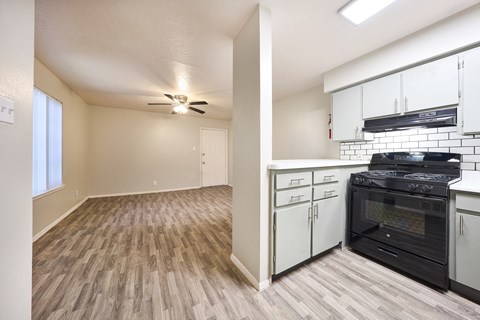 the view of a kitchen and living room with a stove and a ceiling fan
