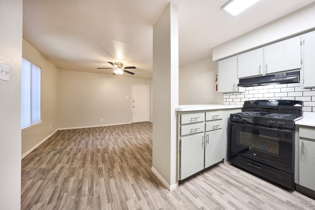 the view of a kitchen and living room with a stove and a ceiling fan