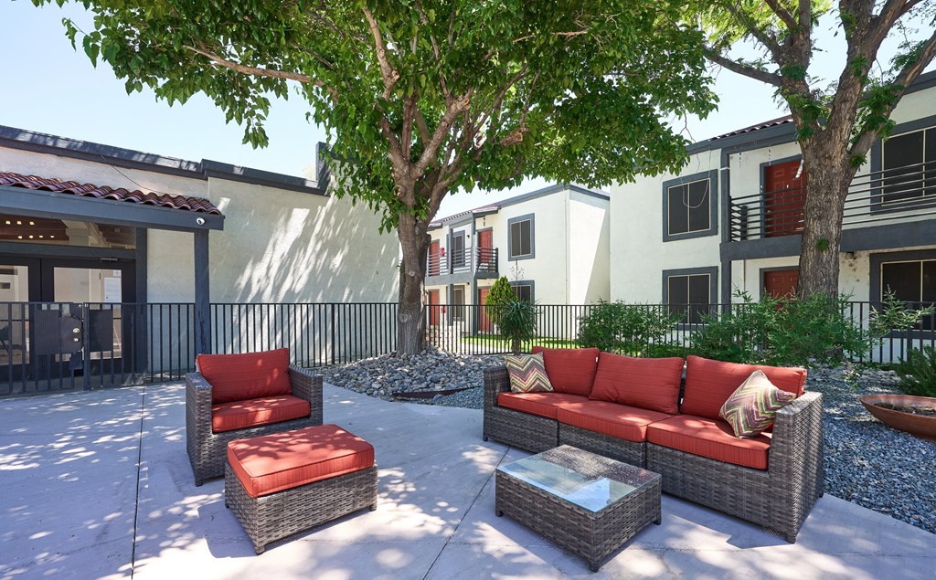 a patio with couches and chairs in front of a building