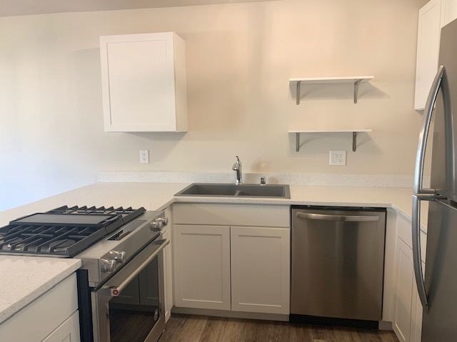 A kitchen with a stove, sink, and refrigerator.