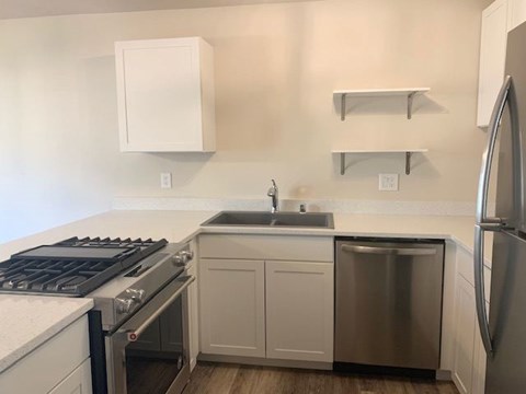 A kitchen with a stove, sink, and refrigerator.