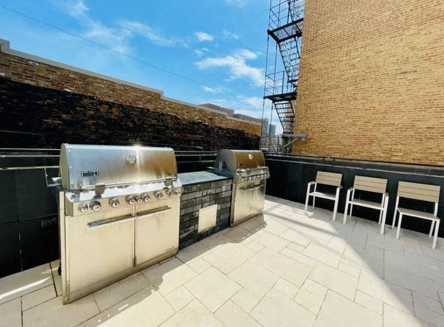 a patio with two barbecue grills and chairs on it