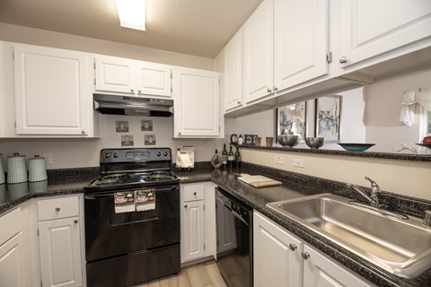 A black stove in a kitchen with white cabinets.