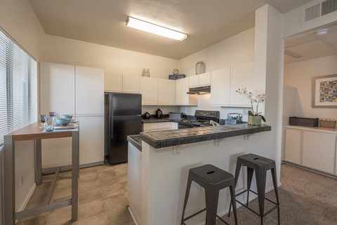 A kitchen with a black refrigerator and white cabinets.