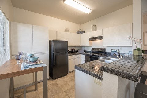 A kitchen with black appliances and white cabinets.