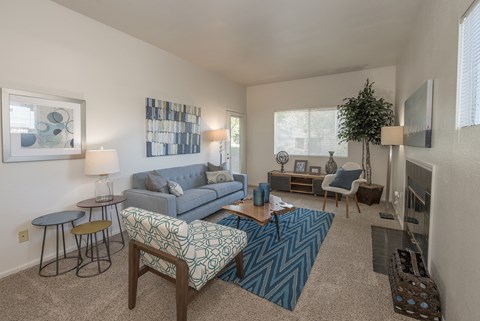 A living room with a blue couch and a patterned chair.