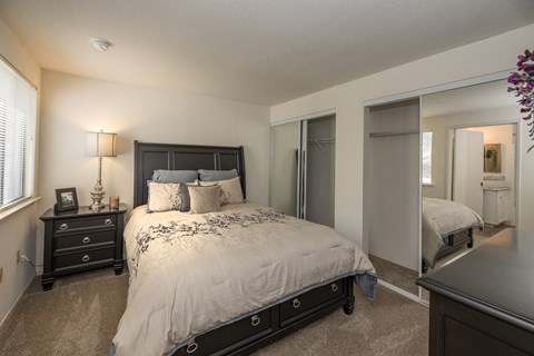 A bedroom with a large bed and a dresser at Bishop's Court Apartments, California, 95670