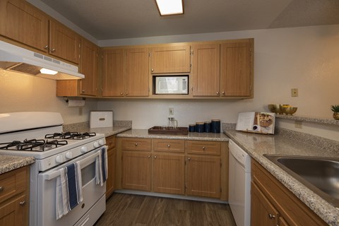 a kitchen with white appliances and wooden cabinets and granite counter tops