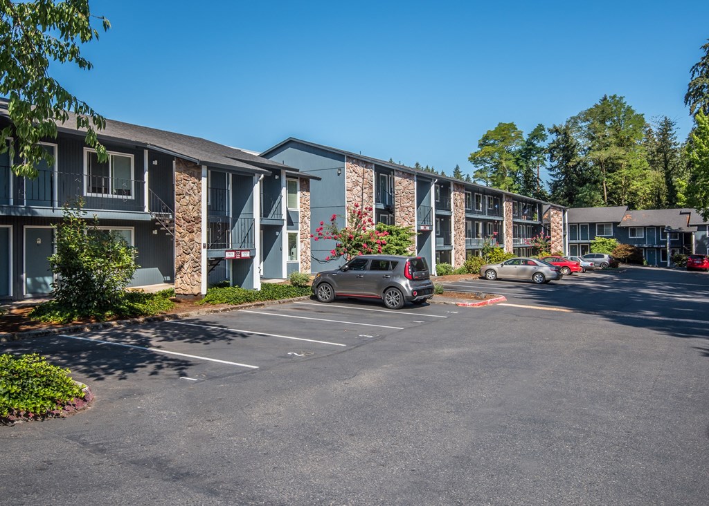 Cedar Lane Apartments two and three story building fronts and parking lot with numbered spaces.