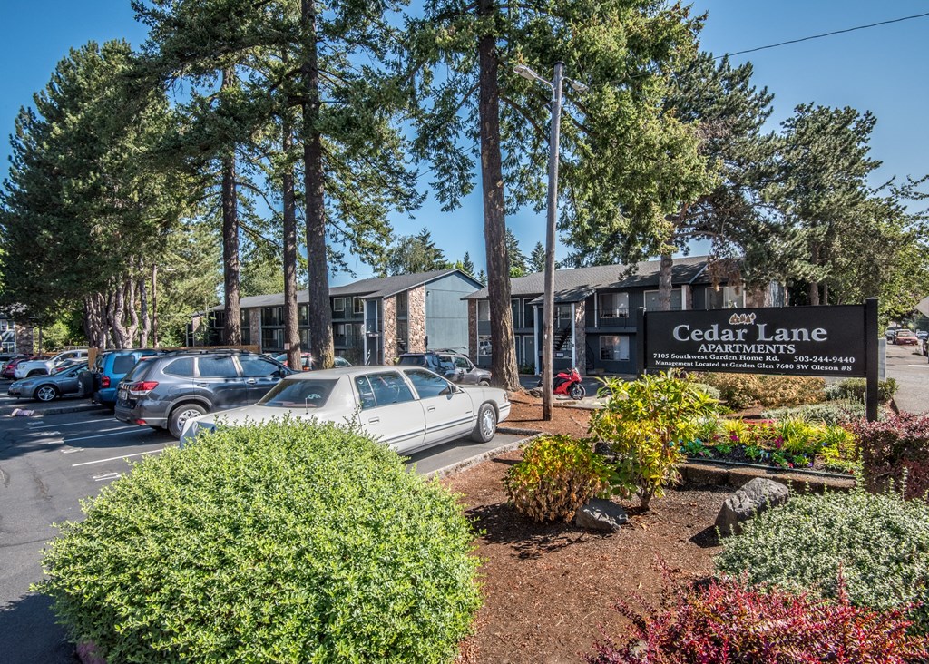 Cedar Lane Apartments monument sign and mature landscaping with buildings in the background