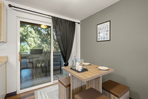 A dining area with a table set for two and a view of trees at Clackamas Trails Apartments, Oregon, 97222