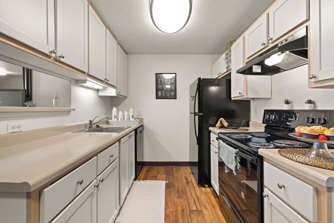 A kitchen with black appliances and white cabinets.