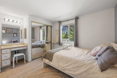 A bedroom with a bed, vanity, and chair at Clackamas Trails Apartments, Oregon, 97222