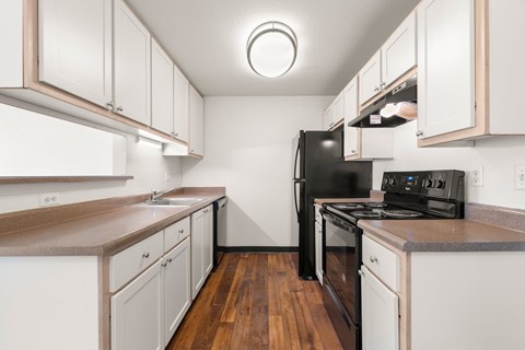 A kitchen with white cabinets and a black fridge.