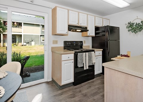 a kitchen with black appliances and white cabinets and a sliding glass door