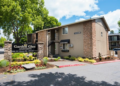 The image shows the front of Garden Glen Apartments with a sign and landscaping.