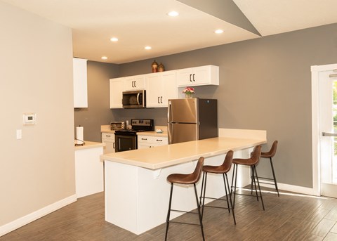 a kitchen with a large island with three bar stools and a refrigerator and microwave