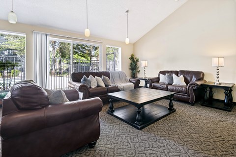 A living room with brown leather furniture and a large window.