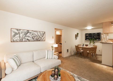 A living room with a white couch and a painting on the wall.