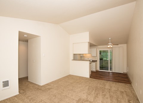 an empty living room and kitchen with white walls and wood flooring
