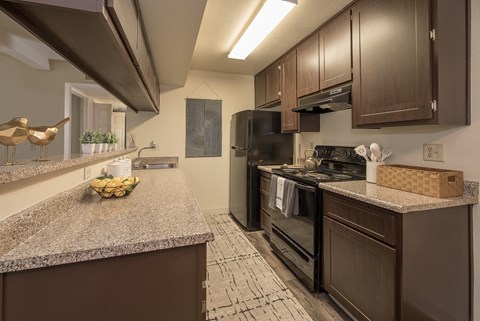 A kitchen with brown cabinets and a black refrigerator.