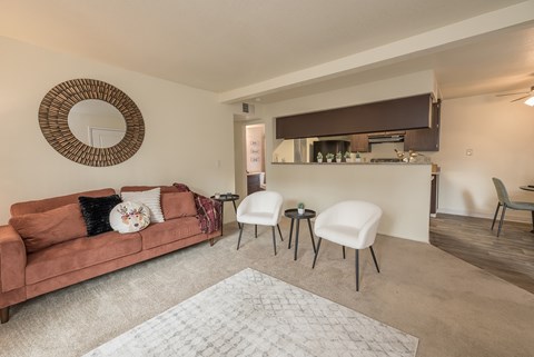 A living room with a brown couch and a round mirror on the wall.