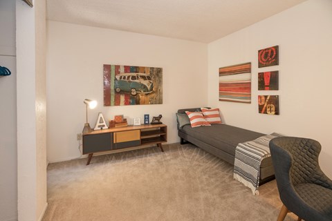 A living room with a grey couch, a chair, a coffee table, and a painting on the wall.