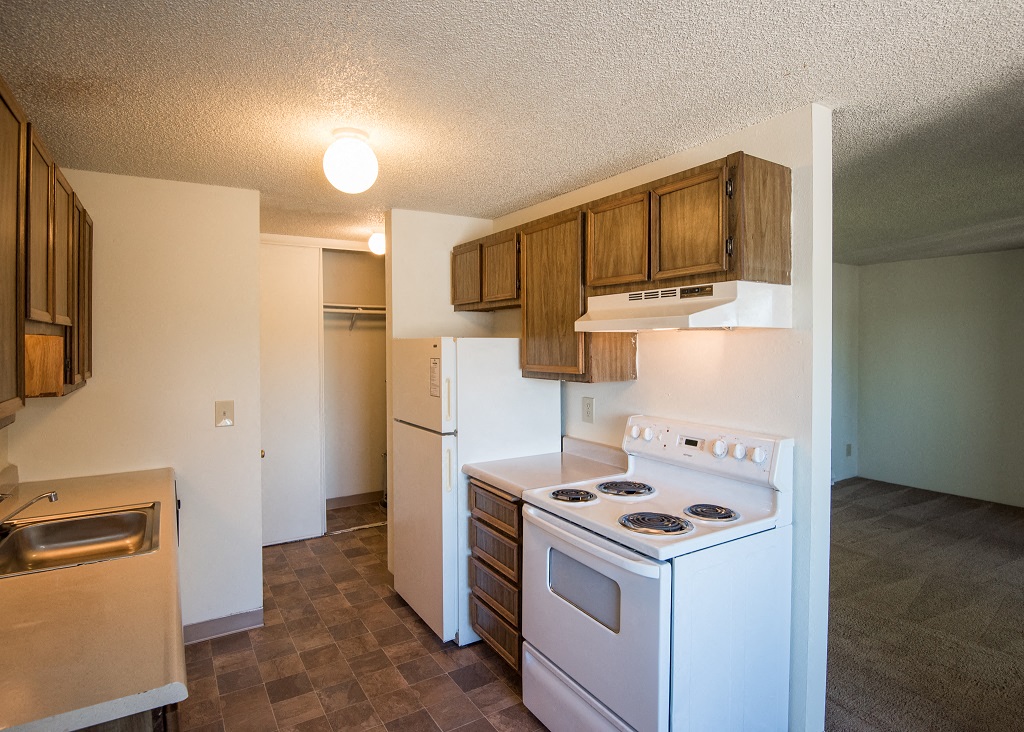 an empty kitchen with white appliances and wooden cabinets