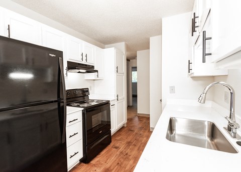 an empty kitchen with black appliances and white cabinets