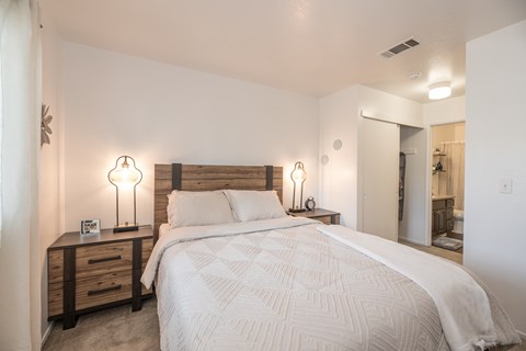 A bedroom with a large bed and two lamps on either side of the bed  at Sierra Glen Apartments, California, 95621