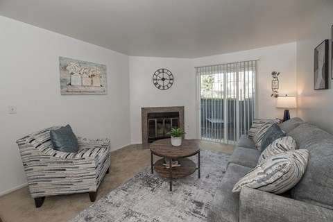 A living room with a grey couch, a wooden coffee table, and a painting on the wall.
