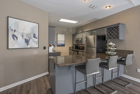 a kitchen with a breakfast bar and a stainless steel refrigerator
