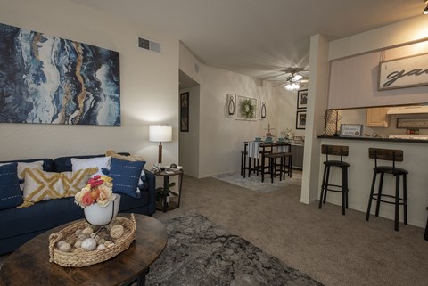 A living room with a blue couch and a painting on the wall.