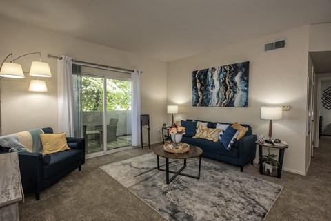 A living room with a blue couch and a painting on the wall.