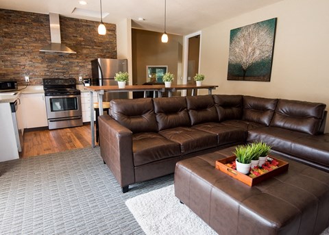 a living room with a brown leather couch and a kitchen