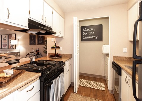 a kitchen with white cabinets and black appliances and a doorway to the laundry room
