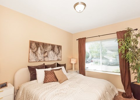 A bedroom with a large bed and a painting on the wall at The Landing Apartments and Townhomes, Oregon, 97045