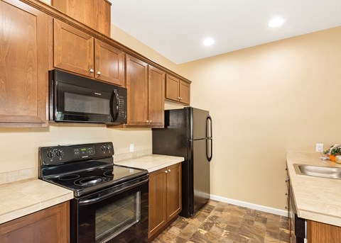 A kitchen with black appliances and wooden cabinets.