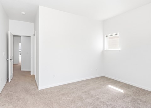 A spacious, empty room with a carpeted floor and a small window at The Landing Apartments and Townhomes, Oregon, 97045
