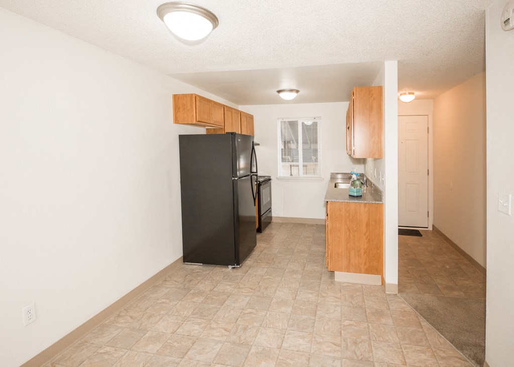 vacant apartment dining area and kitchen with black appliances and wood cabinets at Todd Village Apartments, Tualatin, 97062