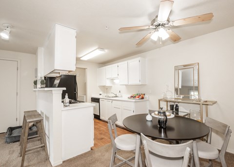 a dining room and kitchen with a ceiling fan and a table and chairs