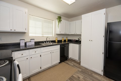 a kitchen with white cabinets and black counter tops and a black refrigerator