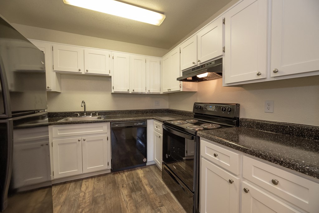 a kitchen with white cabinets and black appliances at Woodbridge Apartments, Sacramento, 95833