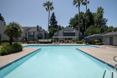 swimming pool and pool deck with  lounge chairs and umbrellas at Woodbridge Apartments, Sacramento, California 95833