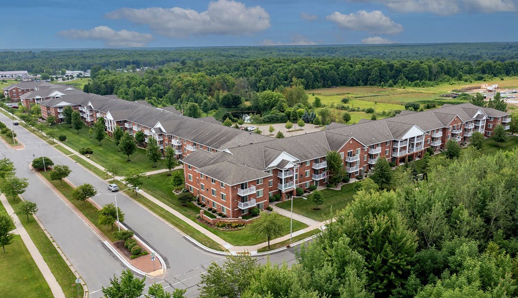 an aerial view of a large apartment complex with a green field in the background