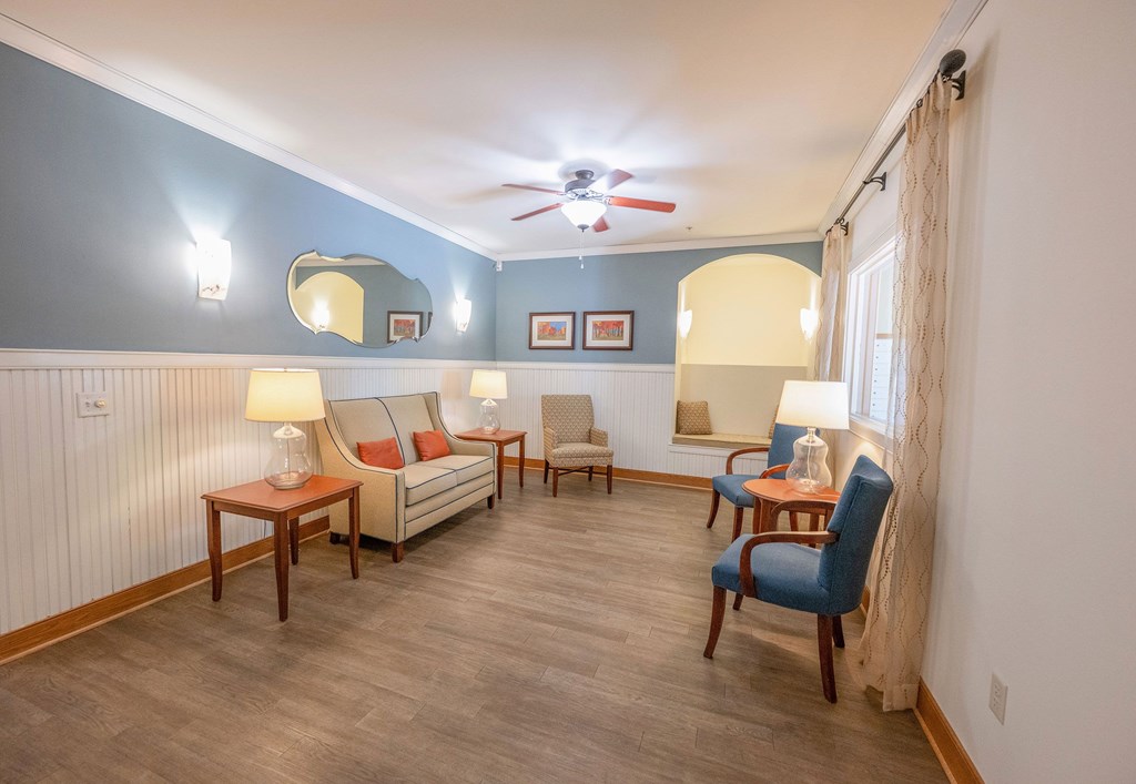 A living room with a sofa, chairs, and a ceiling fan.