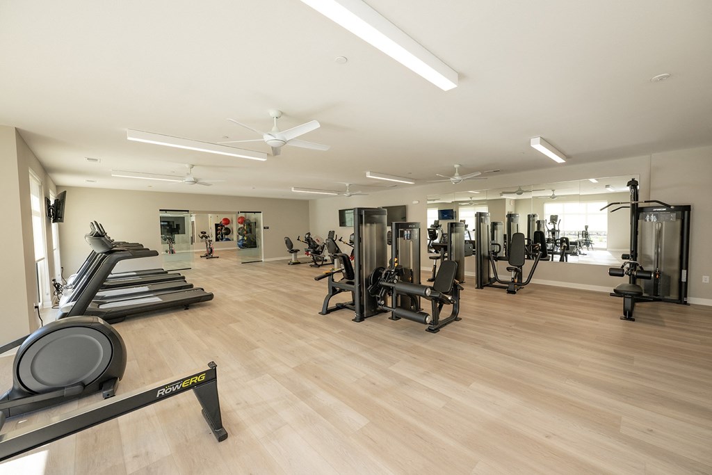 a gym with cardio equipment and weights on a wooden floor