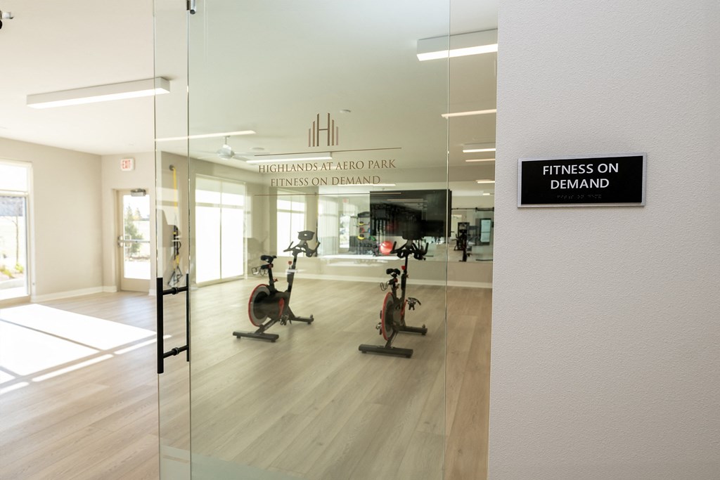 a gym with a sign that reads fitness on demand on a glass wall