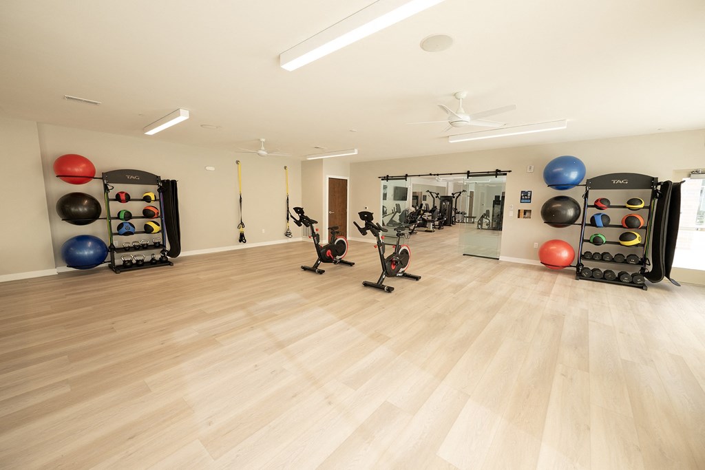 a gym with weights and cardio equipment on a wooden floor